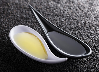 Sesame oil in small bowls on a background of black sesame.