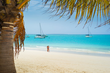 Fototapeta na wymiar tropical beach with yacht and girls under palm tree in Zanzibar in Tanzania