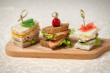 Buffet sandwiches with fish, cheese and cucumbers on the kitchen board. Restaurant menu. - 248359363