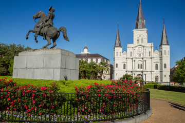 Fototapeta na wymiar St. Louis Cathedral, Jackson Square, Louisiana, United States. Color horizontal image with Andrew Jackson statue in foreground on left with red flowers.