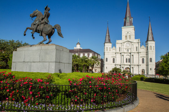 St. Louis Cathedral, Jackson Square, Louisiana, United States. Color horizontal image with Andrew Jackson statue in foreground on left with red flowers.