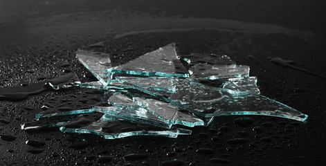Broken glass pile pieces with water droplets isolated on black background and texture