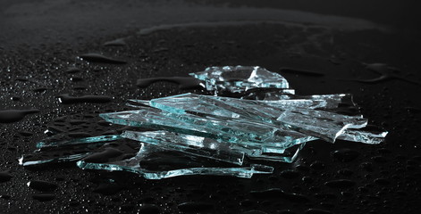 Broken glass pile pieces with water droplets isolated on black background and texture