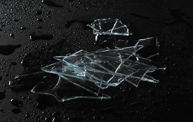Broken glass pile pieces with water droplets isolated on black background and texture