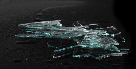 Broken glass pile pieces with water droplets isolated on black background and texture