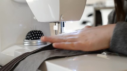 Hands of a seamstress sewing with the machine to sew a zip on the fabric