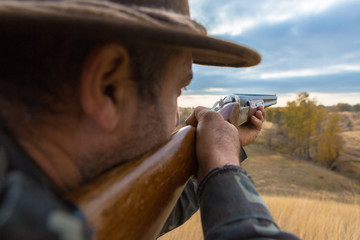 Hunter with a hat and a gun in search of prey in the steppe	