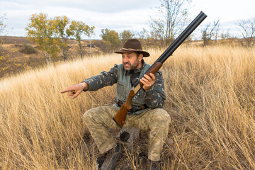 Hunter with a hat and a gun in search of prey in the steppe	