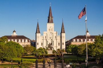 St. Louis Cathedral at sunrise with statue of Andrew Jackson in front and American flag on right...
