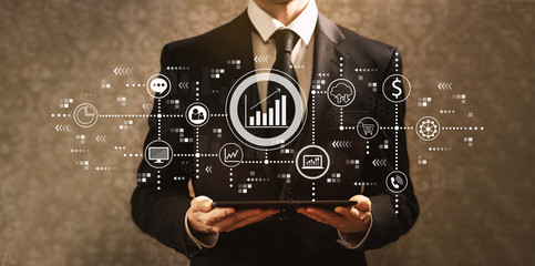 Marketing concept with businessman holding a tablet computer on a dark vintage background