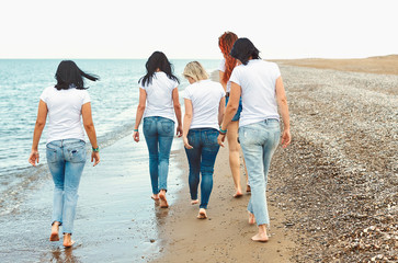 Group of friends women walking on sea beach
