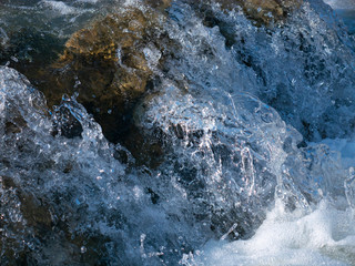 Splashes and drops of water in a small waterfall in winter