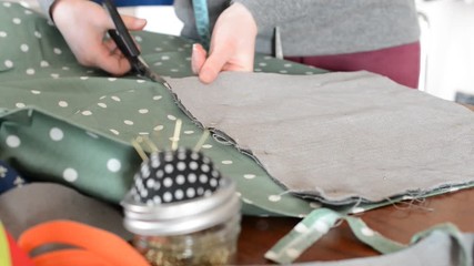 Hands of seamstress who cut the fabric with the scissor
