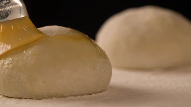 Hand with a brush lubricates dough pies with melange on board filled with flour slow motion close up macro shot food cooking video