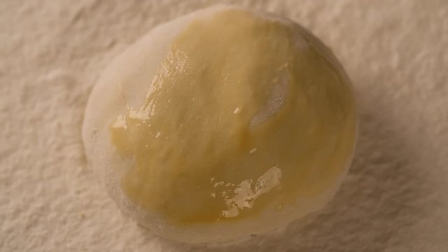 Hand with a brush lubricates dough pie cake with melange on board filled with flour close up macro shot top view food cooking video