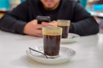 young man with cup of black coffee with cell phone at the coffee restaurant 