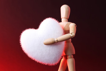 Wooden man holding a heart. Wooden man concept. Wooden mannequin