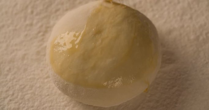 Hand with a brush lubricates dough pie cake with melange on board filled with flour close up macro shot top view food cooking 4K video