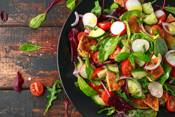 Traditional fattoush salad on a plate with pita croutons, cucumber, tomato, red onion, vegetables mix and herbs