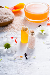 Fototapeta na wymiar aromatherapy: orange gel and extract, bath salt, cosmetic cream, organic soap and petals on white wood