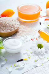 Obraz na płótnie Canvas aromatherapy: orange gel and extract, bath salt, cosmetic cream, organic soap and petals on white wood