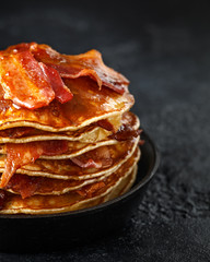 Pancakes with crispy bacon and maple syrup in cast iron skillet, frying pan. Morning Breakfast