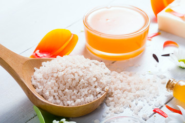 aromatherapy: orange gel and extract, bath salt, cosmetic cream, organic soap and petals on white wood