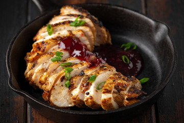 Grilled sliced chicken breast with cranberry sauce in mini cast iron frying pan