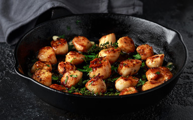 Scallops seared in garlic and parsley butter served in cast iron skillet