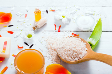 aromatherapy: orange gel and extract, bath salt, cosmetic cream, organic soap and petals on white wood