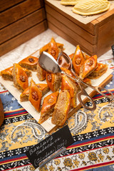 The Holiday Of Navruz. National color.A traditional dish of pakhlava dough.On a brown wooden plate on a silk scarf with a national print Buta.