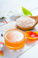 aromatherapy: orange gel and extract, bath salt, cosmetic cream, organic soap and petals on white wood