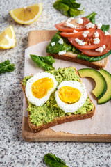 Healthy avocado and egg toasts. Toast, avocado, egg, tomatoes, spinach, cheese Feta, lemon. Organic healthy food. Clean healthy eating