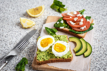 Fototapeta na wymiar Healthy avocado and egg toasts. Toast, avocado, egg, tomatoes, spinach, cheese Feta, lemon. Organic healthy food. Clean healthy eating
