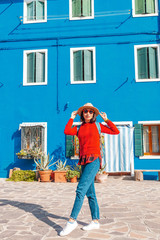 young happy traveler woman posing among colorful houses on Burano island, Venice. Tourism in Italy concept