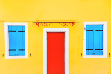 Yellow house with red Door in the village of Burano, Venice