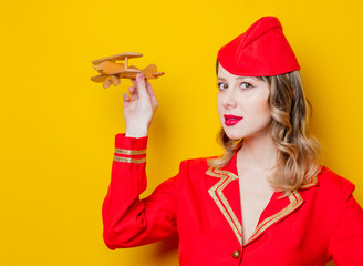 charming vintage stewardess wearing in red uniform with airplane