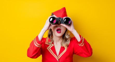 charming vintage stewardess wearing in red uniform with binoculars