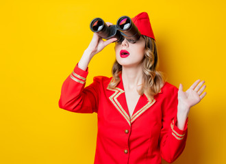 charming vintage stewardess wearing in red uniform with binoculars