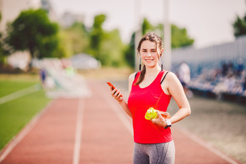 Theme sport health. girl standing resting on track. stadium road uses technodogies. hand phone ear...