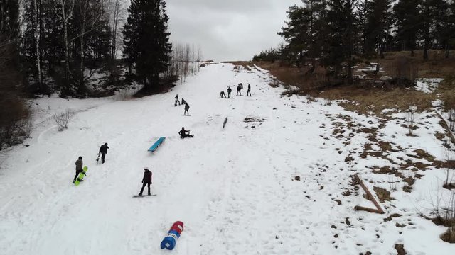 Aerial view: snowboarders going down the slope in winter day. Snowboarders enjoying on slopes of ski resort in winter season. 4K video, aerial footage.