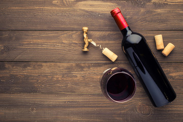 Glass bottle of wine with corks on wooden table background.Top view with copy space