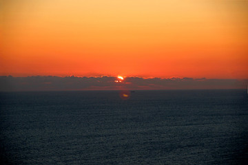 Beautiful sunset over the sea. The sun has a beautiful orange and red color.