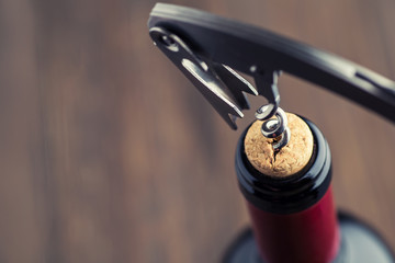 Wine bottle with corkscrew on wooden background