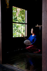 Femme à la fenêtre du temple personnel de sa maison en bois