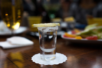 shot glass filled with tequila service with lemon and salt