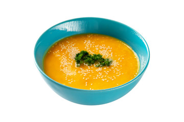 Closeup bowl of pumpkin soup decorated with parsley and sesame isolated at white background. Concept of healthy lifestyle.