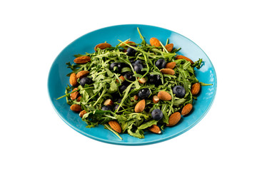 Closeup plate of fresh vegetables vegetarian healthy salad with aragula, nuts, blueberry isolated at white background.