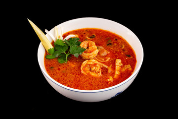Bowl of traditional vietnamese soup tom yum with prawns and seafood isolated at black background.