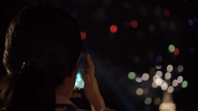 Asian lady take a picture of fireworks with smartphone. Specific on Songkran day.